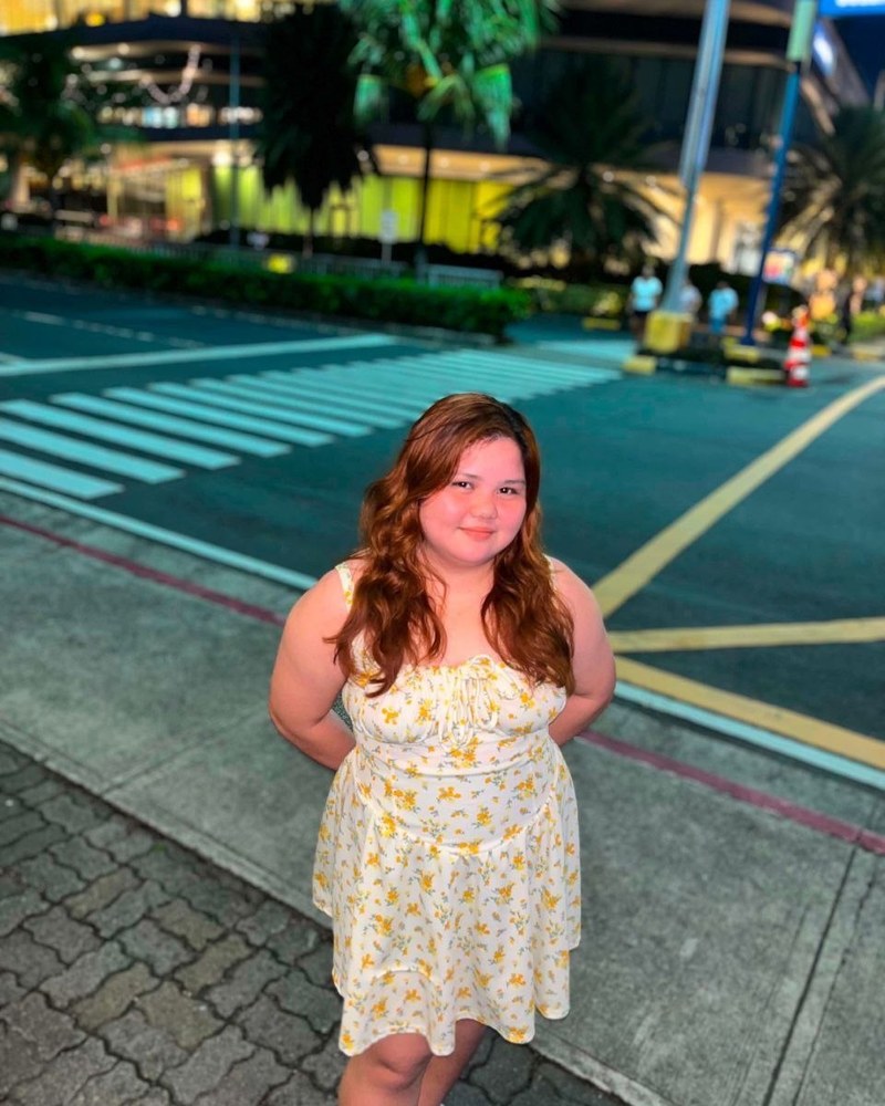 Cricel smiling in a yellow floral dress at night